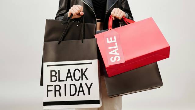 Black Friday Frau hält Einkaufstüten mit "Black Friday" und "Sale" Aufschrift in der Hand