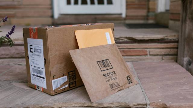 Paket und Versandtasche mit Versandetikett vor Haustür