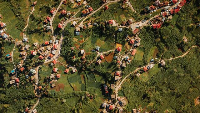Luftaufnahme einer kleineren Stadt mit Wohnhäusern, Straßen und grünen Flächen.