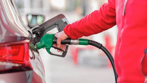 Person betankt ein Auto an einer Tankstelle mit einer grünen Zapfpistole.