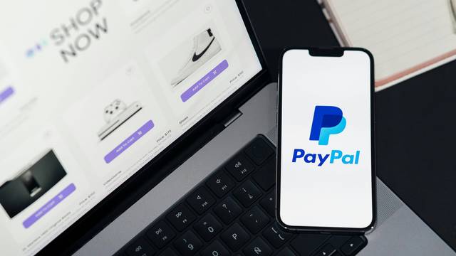 PayPal Logo auf Smartphone-Bildschirm. Links ein Laptop.