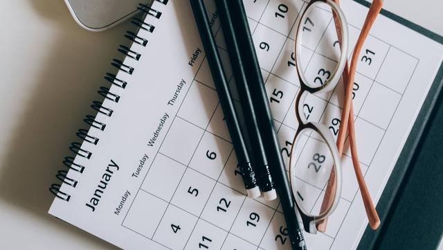 Stifte und eine Brille liegen auf einem Kalender