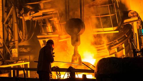 Arbeiter steht in Stahlfabrik vor Hochofen