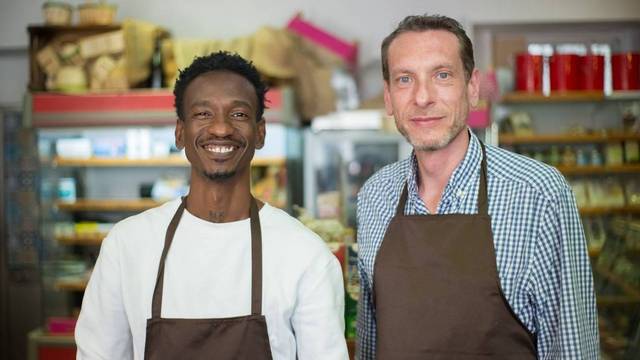 Zwei Unternehmer stehen lächelnd in einem kleinen Lebensmittelgeschäft. Zwei Unternehmer stehen lächelnd in einem kleinen Lebensmittelgeschäft.