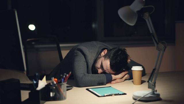Mann schläft mit Kopf auf Schreibtisch Mann schläft mit Kopf auf Schreibtisch