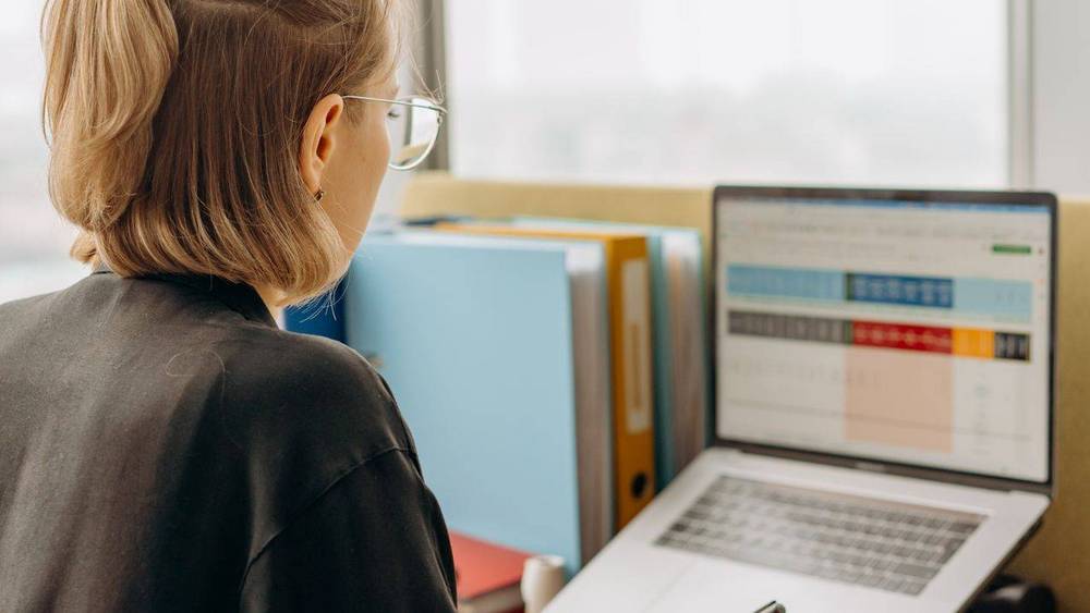 Mitarbeiterin arbeitet am Laptop mit einer digitalen Tabelle im Büro.
