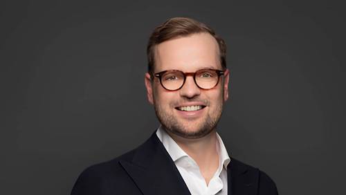 Porträt von Franchise-Experte Jan Schmelzle mit Brille vor dunklem Hintergrund