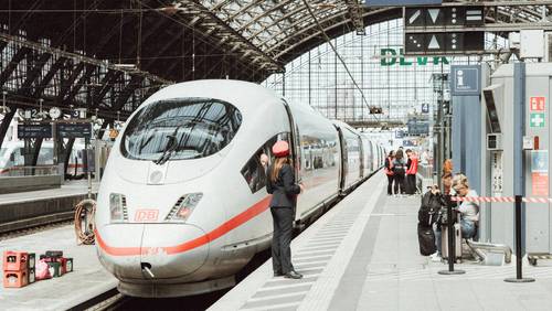 ICE im Bahnhof. Bahn-Mitarbeiterin im Vordergrund.