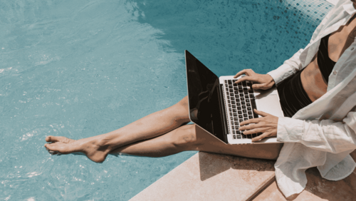 Frau mit Laptop arbeitend am Pool