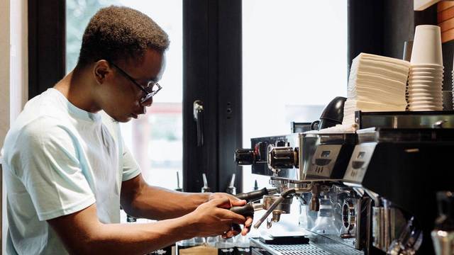 Ein Mitarbeiter bedient eine Kaffeemaschine in einem Café