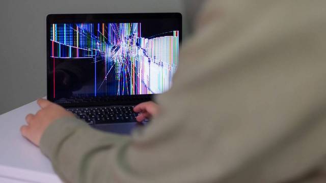 Person sitzt vor beschädigtem Laptop Person sitzt vor beschädigtem Laptop