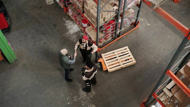 Logistik-Arbeiter Arbeiter in Logistik-Lager unterhalten sich, Drohnenaufnahme.